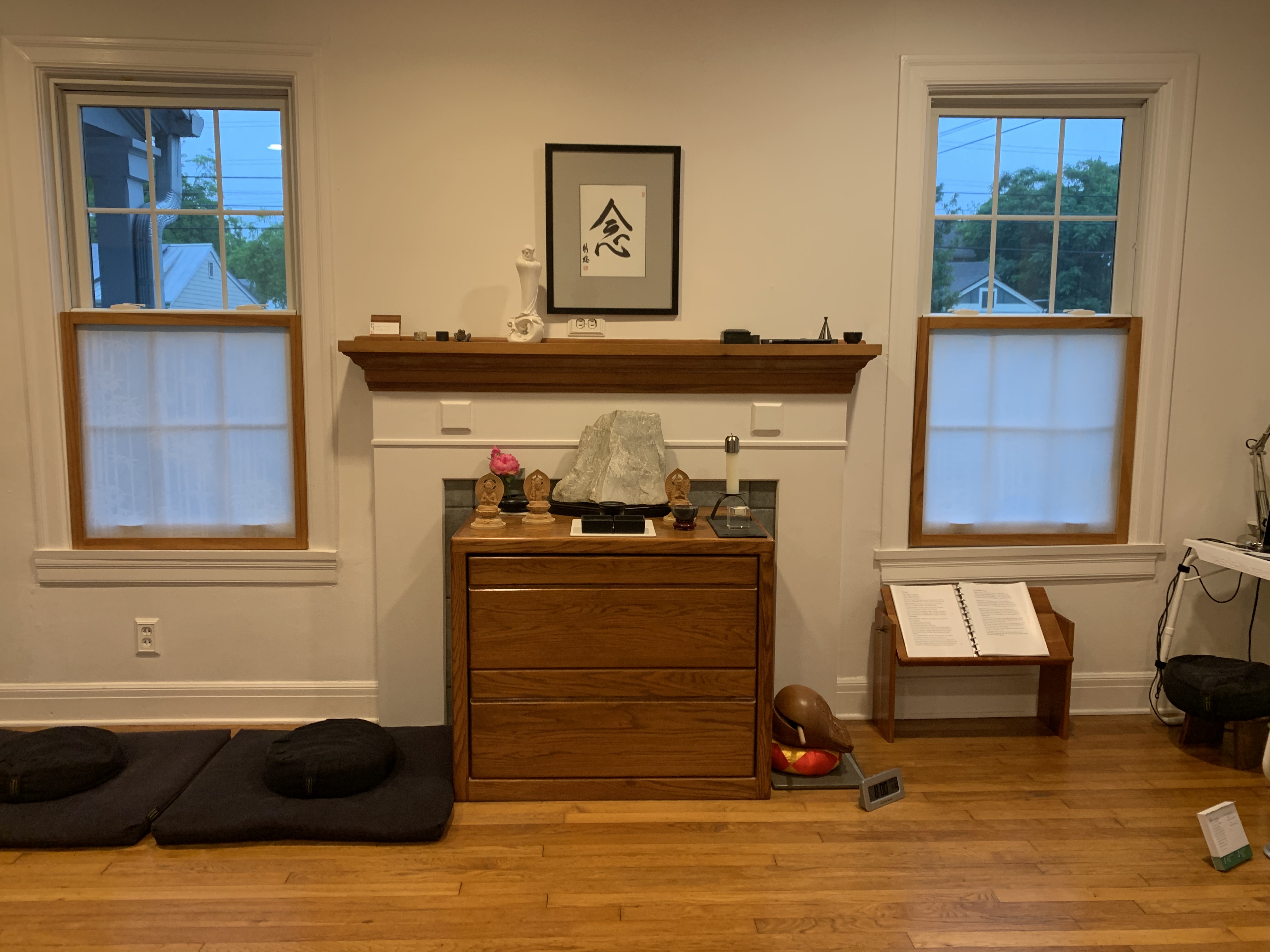 The Appamada zendo — altar with calligraphy, zafu cushions, mokugyo bell, and sutra stand